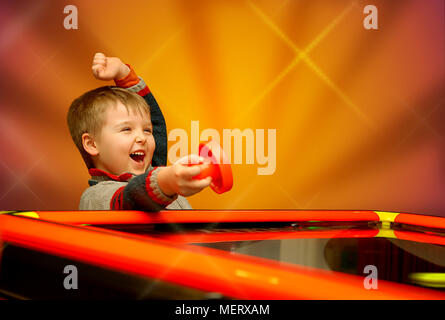 A child who has won his air hockey game, with a red mallet in his hand. Stock Photo