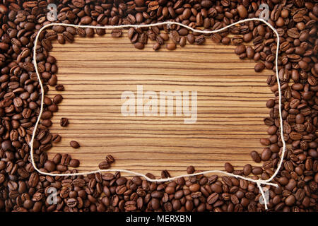 Frame, made of coffee beans and natural grass rope on zebrano wood background. Stock Photo