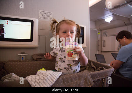 14 month old girl sitting up in bassinet on a Singapore Airlines