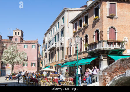 Campo Santa Maria Nova in spring, Cannaregio, Venice, Veneto, Italy with people eating at an open air restaurant and a tree with white blossom Stock Photo