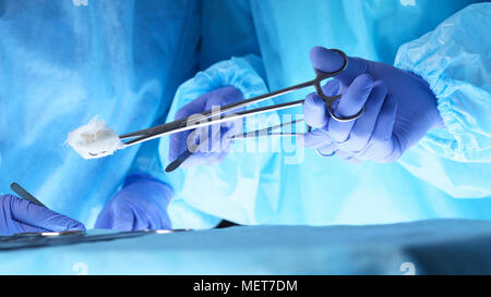 Surgeons hands holding surgical scissors and passing surgical equipment, close-up. Health care and veterinary concept Stock Photo