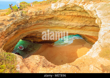 Benagil, Portugal - August 23, 2017: Benagil Cave seen from the top of rocky cliff in Algarve coast. Aerial view of famous sea caves with boat trips leading to visit the caves from Praia de Benagil. Stock Photo