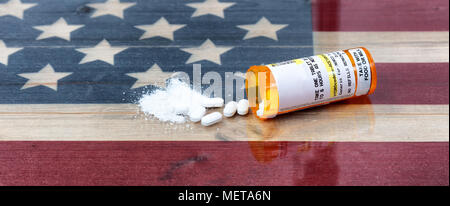 Bottle of prescription for Hydrocodone or generic opioid with crushed or whole pain killer tablets. Rustic USA flag in background for drug addiction c Stock Photo
