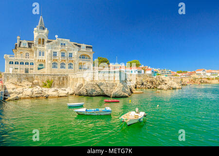 Scenic landscape of abandoned Palace Seixas and boats on the waterfront of Cascais, Lisbon Coast in Portugal. Praia da Rainha on the distance. Turquoise sea in summertime. Copy space with blue sky. Stock Photo