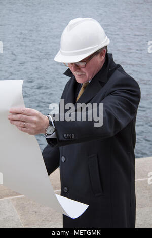 Business construction man engineer architect with blueprint on the work site overlooking project at waterfront site Stock Photo