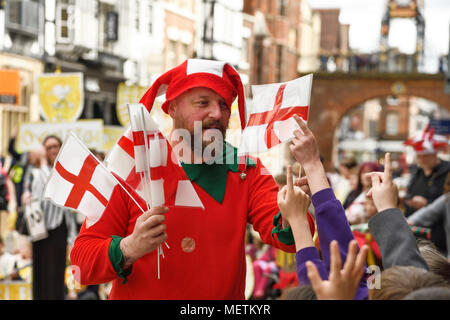 Chester, UK. 23rd April 2018. A jester hands out flags in the St George's Day parade through Chester city centre. The parade includes street performance, theatre and music with local school children performing many supporting roles. Credit: Andrew Paterson/Alamy Live News Stock Photo