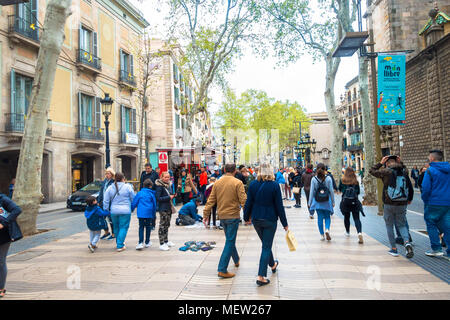 La Rambla in Barcelona, busy with tourists. Lined by trees sprouting into leaf, the road is flanked by shops and restaurants. Stock Photo
