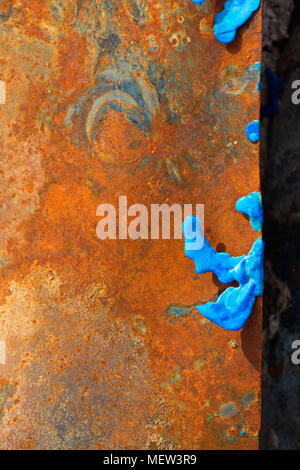 Blue melted plastic is covering rusty sheet metal on a burned up garbage heap Stock Photo