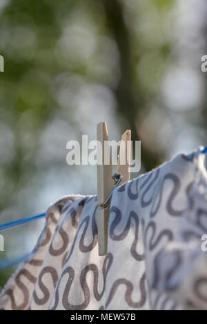 Close up of clothes pegs securing washing hanging to dry in a garden on a sunny summer day. Stock Photo