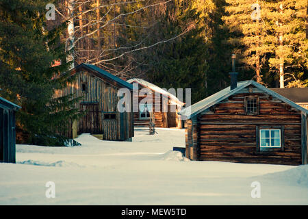 Wooden log house in a snowy winter forest at sunset Stock Photo