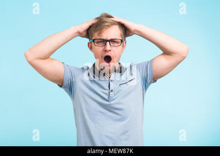 Shocked or surprised young man on blue background Stock Photo
