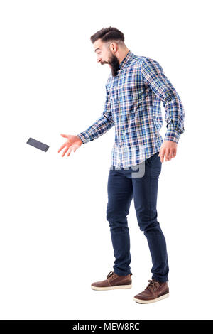 Screaming shocked young bearded man dropping mobile phone falling on the ground in mid air. Full body isolated on white background. Stock Photo