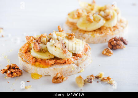 Crisp bread banana and peanut butter snack. Healthy breakfast with walnuts and honey. High key diet concept. Stock Photo