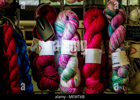 Multi-coloured skeins of wool lit by a spotlight on a retailers stand at Yarndale, Skipton, North Yorkshire, UK. Stock Photo