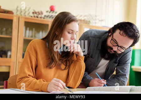Young male hispanic teacher helping his student in chemistry class. Education, Tutoring and Encouragement concept. Stock Photo