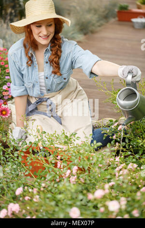 Smiling gardener woman watering flowers in the garden Stock Photo