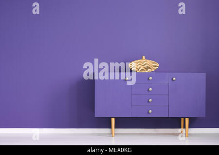 Gold vase on violet cabinet against the wall with copy space in anteroom interior Stock Photo