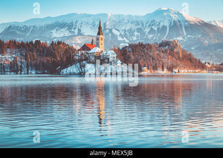 Beautiful view of famous Bled Island (Blejski otok) at scenic Lake Bled with Bled Castle (Blejski grad) and Julian Alps in the background at sunrise Stock Photo