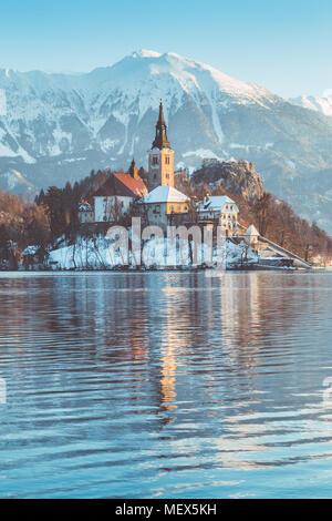 Beautiful view of famous Bled Island (Blejski otok) at scenic Lake Bled with Bled Castle (Blejski grad) and Julian Alps in the background at sunrise Stock Photo