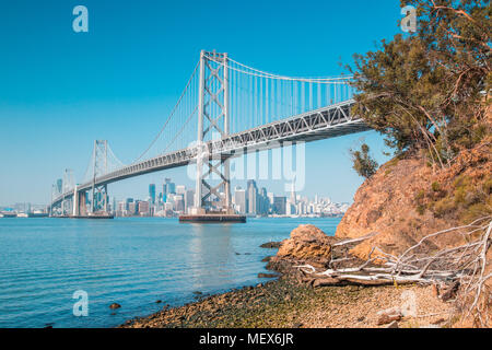 Classic panoramic view of San Francisco skyline with famous Oakland Bay Bridge illuminated on a sunny day with blue sky in summer, San Francisco Stock Photo