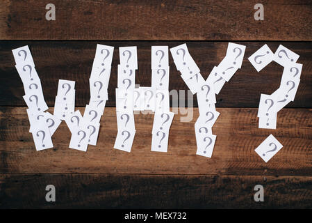 white paper note with question mark arranged to make a WHY word on wooden table. WHY concept background Stock Photo