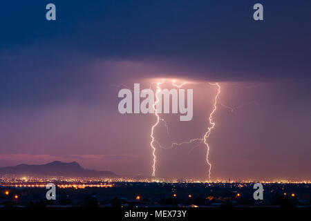 A pair of dramatic cloud to ground lightning bolts strike the city and illuminate the sky during a storm in El Paso, Texas Stock Photo