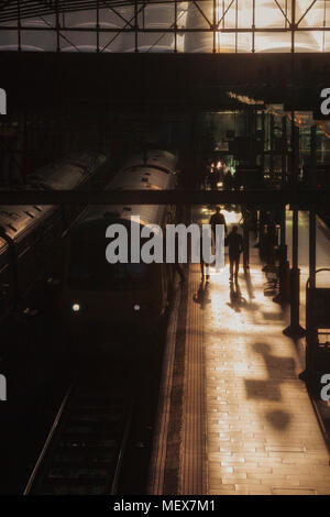 Silhouettes of passengers boarding a Northern rail class 323 electric train at  Manchester Piccadilly railway station on a summer evening Stock Photo