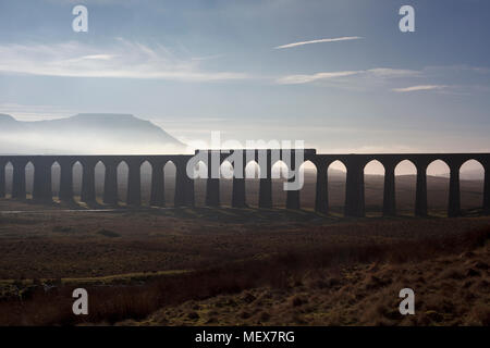 A Northern rail class 153 + 156 sprinter trains cross Ribblehead viaduct on the Settle to Carlisle railway with a misty Ingleborough behind