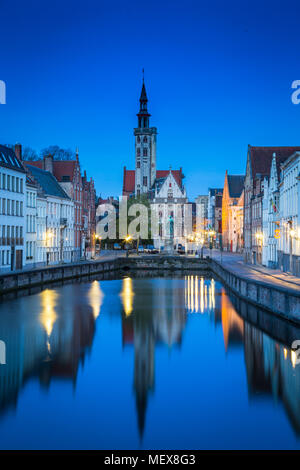 Beautiful panoramic view of famous Spiegelrei canal with famous Poortersloge and Jan van Eyck square in the background at dusk, Brugge, Belgium Stock Photo