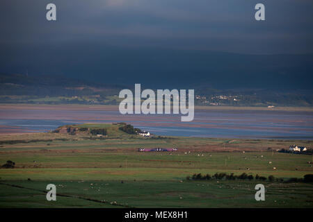 A Northern rail class 156 sprinter train passing the Duddon estuary  at Askam (north of Barrow In Furness) on the Cumbrian coast railway line Stock Photo