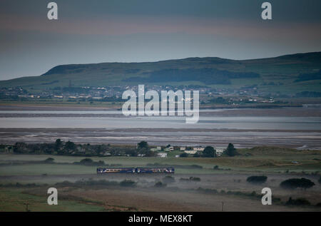 A Northern rail class 156 sprinter train passing the Duddon estuary  at Askam (north of Barrow In Furness) on the Cumbrian coast railway line Stock Photo