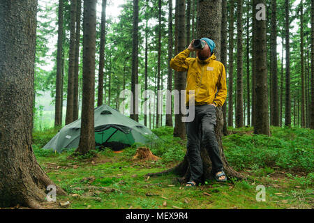 portrait of a caucasian male hiker standing in a forest holding a mug with coffee Stock Photo