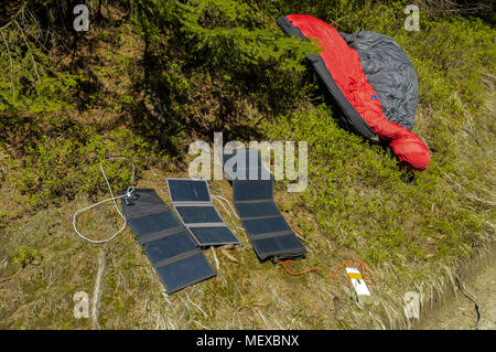 three portable solar panels recharging a batteries from a sun, outdoors on a hiking trail Stock Photo