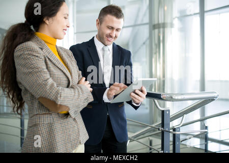 Positive businessman with assistant using tablet Stock Photo