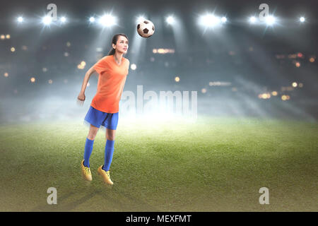 Professional asian football ployer woman jump with ball on the match Stock Photo