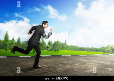 Young asian businessman in formal suit running on the road Stock Photo