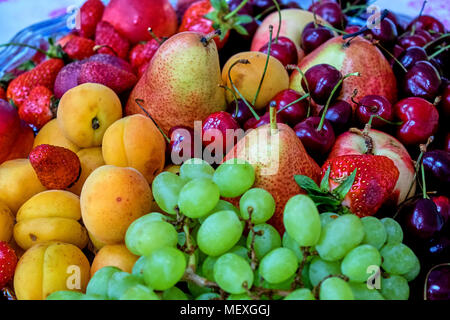 A lot of fruits and berries lying on the table apples, grapes, apricots, cherry, strawberry, pear Stock Photo