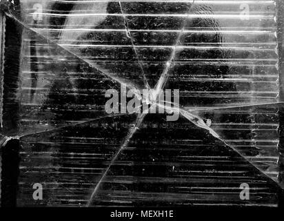 Big crack on the square piece of the glass wall right in the middle of some man refletion black and white texture, background Stock Photo