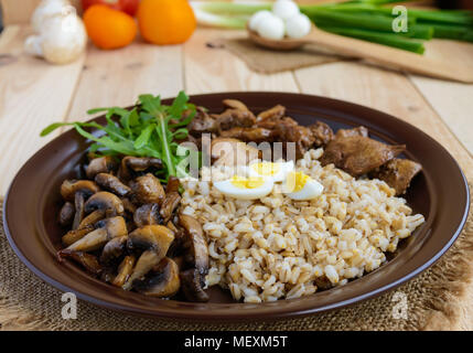 Barley porridge, fried mushrooms and duck liver, boiled quail eggs, tomatoes, arugula - healthy food. Stock Photo