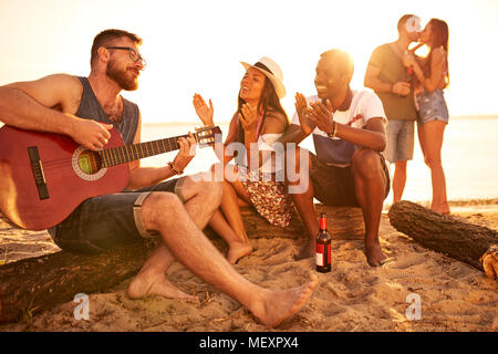 Inspired man playing guitar and singing song on beach Stock Photo