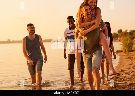 Cheerful friends walking together over coastline Stock Photo