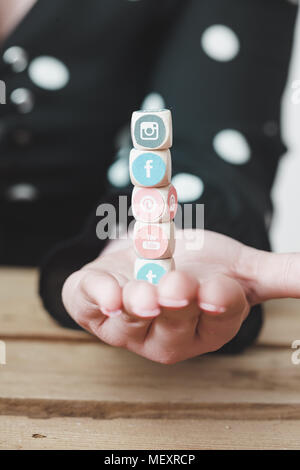 BERLIN, APRIL 5, 2018: Young business person holding cubes with logos of multiple social network websites, symbolic image for management of online pub Stock Photo