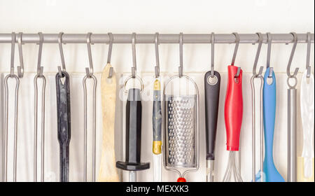 Many different kitchenware hanging on a white kitchen wall Stock Photo