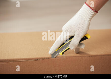 Opening cartoon moving box with mounting knife Stock Photo