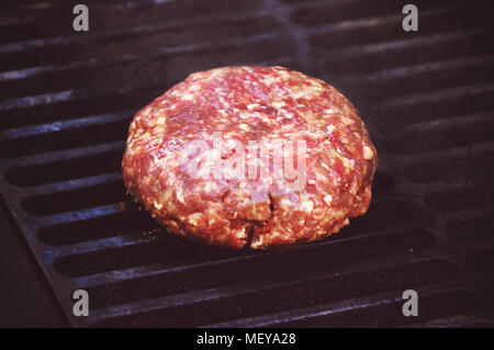 cooking burgers on hot grill. Big thick Patty of ground beef with on the grill. Raw Patty of fresh ground beef Stock Photo