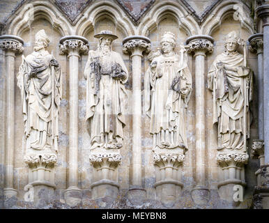 Sculpted stone statues (from the left, Sts Ambrose, Jerome, Gregory and Augustine) on the exterior west wall at the medieval cathedral of Salisbury, E Stock Photo