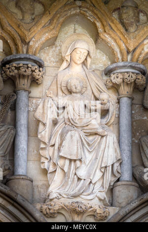 Sculpted stone statue of Mary and Jesus on the wall above the west door entrance at the medieval cathedral of St Mary the Virgin at Salisbury, England Stock Photo