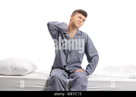 Teenager seated on a bed experiencing neck pain isolated on white background Stock Photo