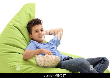 Boy with a bowl of popcorn sitting on a beanbag isolated on white background Stock Photo