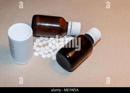 a white jar of pills and two bottles of medical drugs on the cardboard background Stock Photo